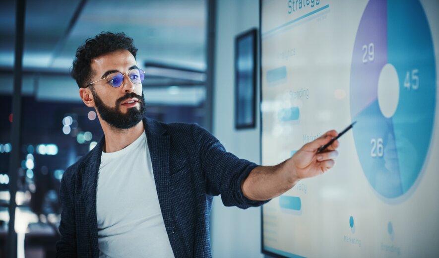 Mann präsentiert Datenanalyse auf großem digitalen Display im Büro
